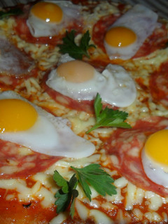 Una foto de Pizza con salame y huevos de codorniz