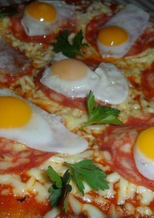 Una foto de Pizza con salame y huevos de codorniz