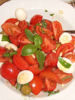 Una foto de Ensalada sencilla de tomates, piñones y albahaca con huevos de codorniz