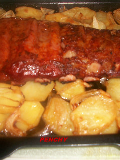Una foto de Costilla adobada al horno sobre cama de patatas a lo pobre