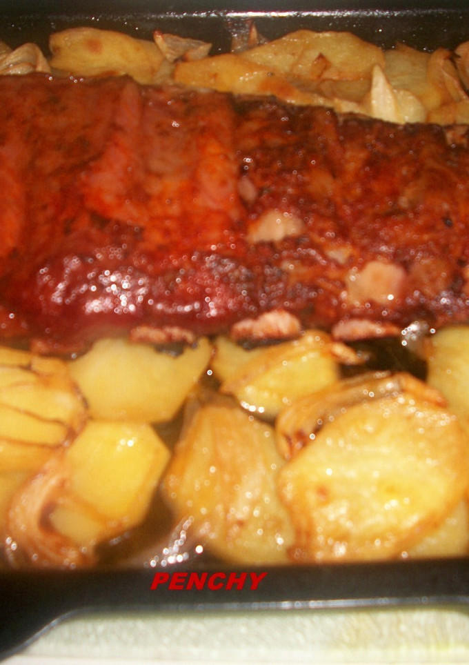 Una foto de Costilla adobada al horno sobre cama de patatas a lo pobre