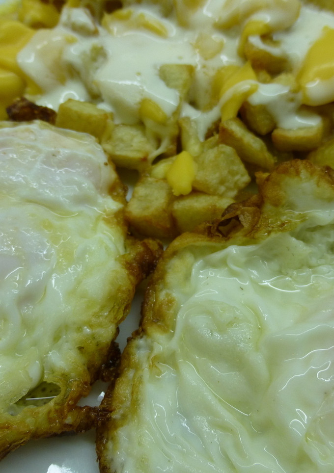 Una foto de Patatas fritas con salsa de yogur y huevos fritos