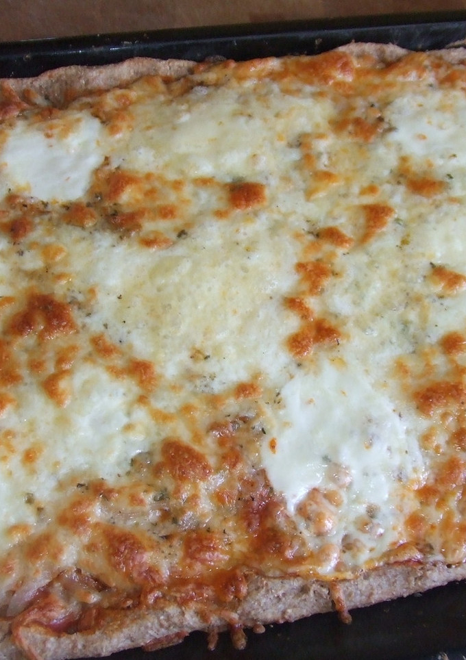 Una foto de Pizza integral cuadrada con cebolla y quesos variados