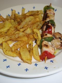 Una foto de Pinchos de pollo y verduras con patatas fritas