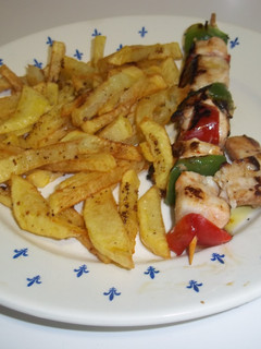 Una foto de Pinchos de pollo y verduras con patatas fritas