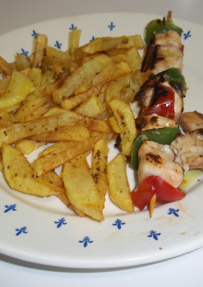 Una foto de Pinchos de pollo y verduras con patatas fritas