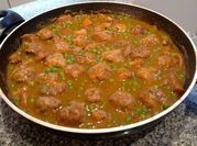 Una foto de albóndigas con salsa de tomate y arvejas
