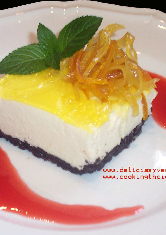 Una foto de Cheesecake de chocolate blanco y limón con coulis de frutillas y cáscaras confitadas de cítricos