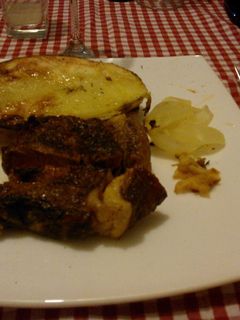 Una foto de Asado a la parrilla de bife de chorizo con ajo, cebolla y papas