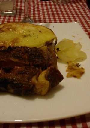 Una foto de Asado a la parrilla de bife de chorizo con ajo, cebolla y papas