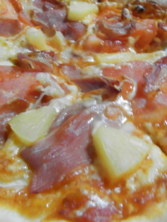 Una foto de Pizza de tomate, jamón serrano y piña