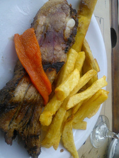 Una foto de Asado a la parrilla de pecho de chancho con fritas
