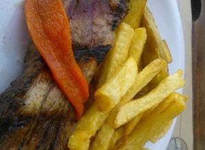 Una foto de Asado a la parrilla de pecho de chancho con fritas