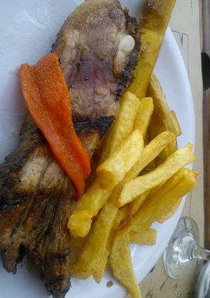 Una foto de Asado a la parrilla de pecho de chancho con fritas