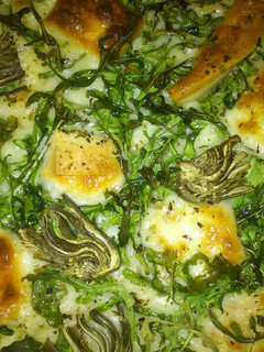 Una foto de Pizza de rúcula, alcachofa y queso
