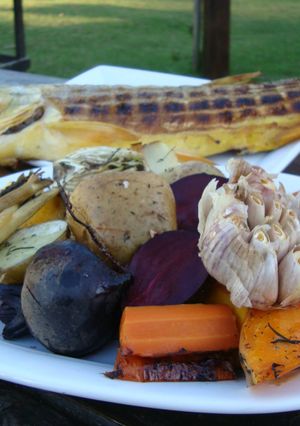 Una foto de Dorado a la estaca con vegetales en horno a leña