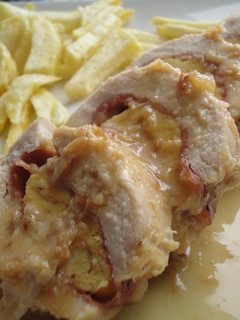 Una foto de Pechuga de pollo rellena de jamón, queso y tortilla en salsa de vino y cebolla
