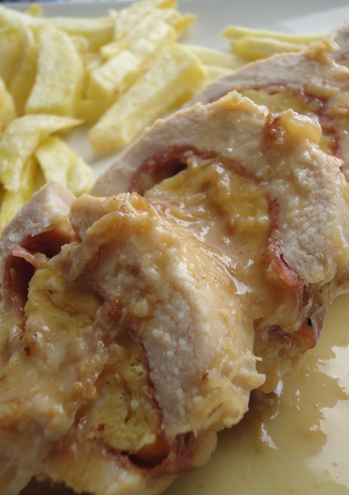 Una foto de Pechuga de pollo rellena de jamón, queso y tortilla en salsa de vino y cebolla