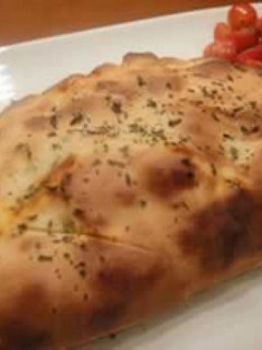 Una foto de Calzone con provolone, salchicha y chimichurri