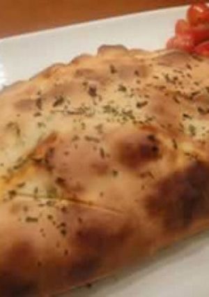 Una foto de Calzone con provolone, salchicha y chimichurri