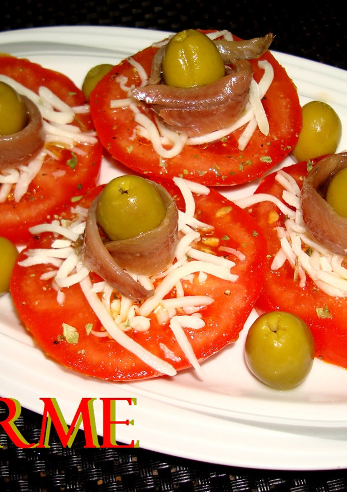 Una foto de Ensalada de tomate con anchoas, queso y aceitunas
