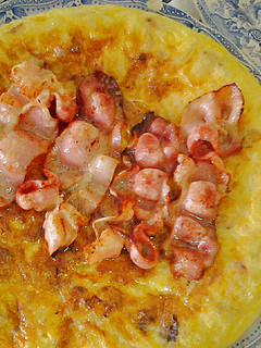 Una foto de Tortilla de patatas con bacón y su jugo por encima