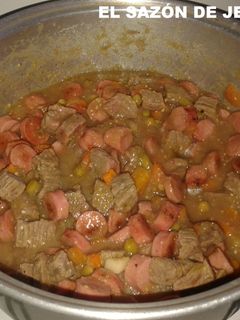 A picture of Carne de res de brocheta en salsa verde con salchichas.