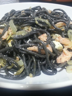 Una foto de Espaguetis al nero di sepia con salmón ahumado y queso feta