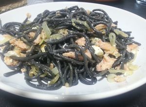 Una foto de Espaguetis al nero di sepia con salmón ahumado y queso feta
