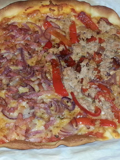 Una foto de Pizza casera mitad de atún y pimiento, mitad de bacon y cebolla