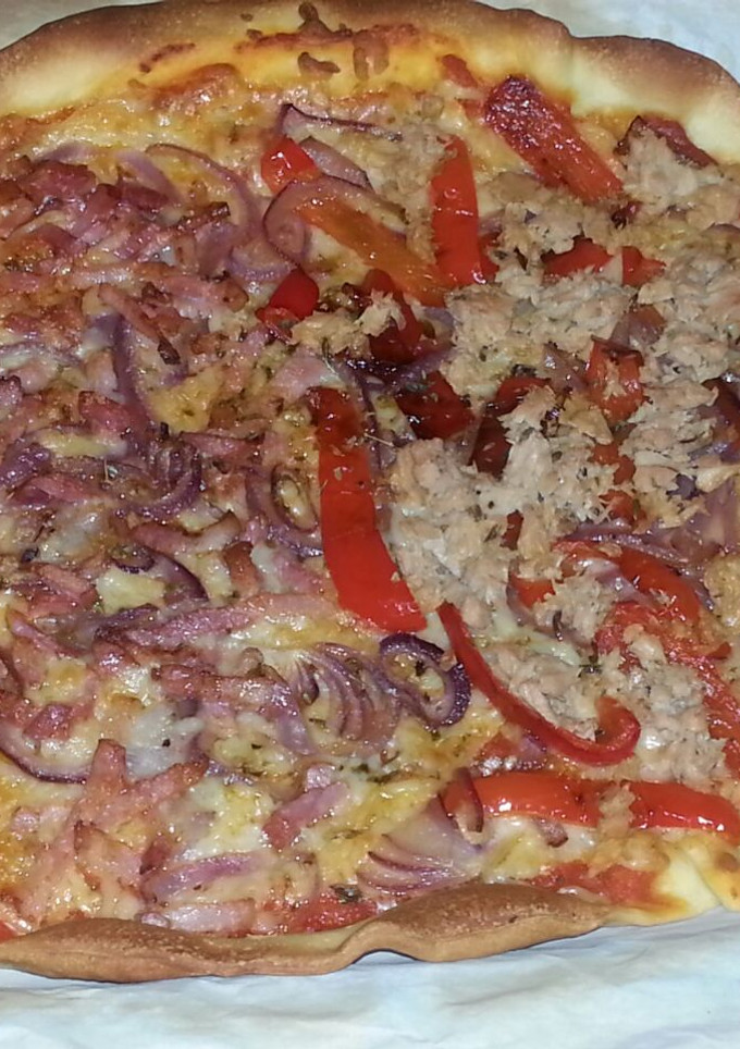 Una foto de Pizza casera mitad de atún y pimiento, mitad de bacon y cebolla