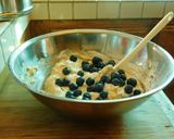 A picture of step 5 of COCONUT MUFFINS with blue berries and chocolate chips.