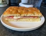 A picture of step 5 of Focaccia bread with Mortadella, grilled tomatoes, melted mozzarella and cornichons.