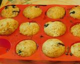 A picture of step 7 of COCONUT MUFFINS with blue berries and chocolate chips.