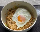 A picture of step 7 of Jah Jan Mien (instant packet noodles) with peanut butter, spring onions topped with fried egg.