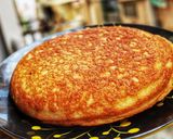 A picture of step 6 of Poda pitha or burnt pitha is a slow cook pitha made from black gram fermented rice.